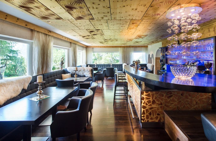 Bar moderno dell'hotel con illuminazione elegante, mobili scuri e comode sedie in un interno dal design elegante con elementi in legno. - Bild größer darstellen